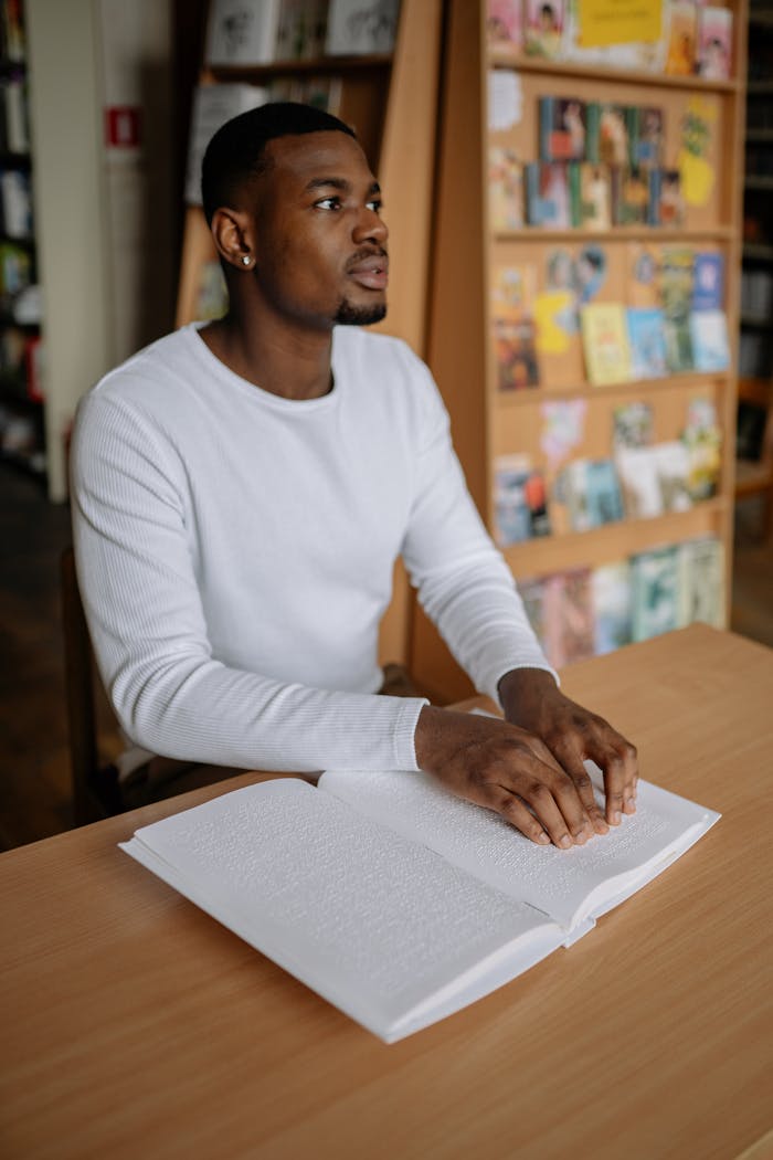 why-choose-us Man attentively reading a Braille book indoors, highlighting literacy and accessibility.