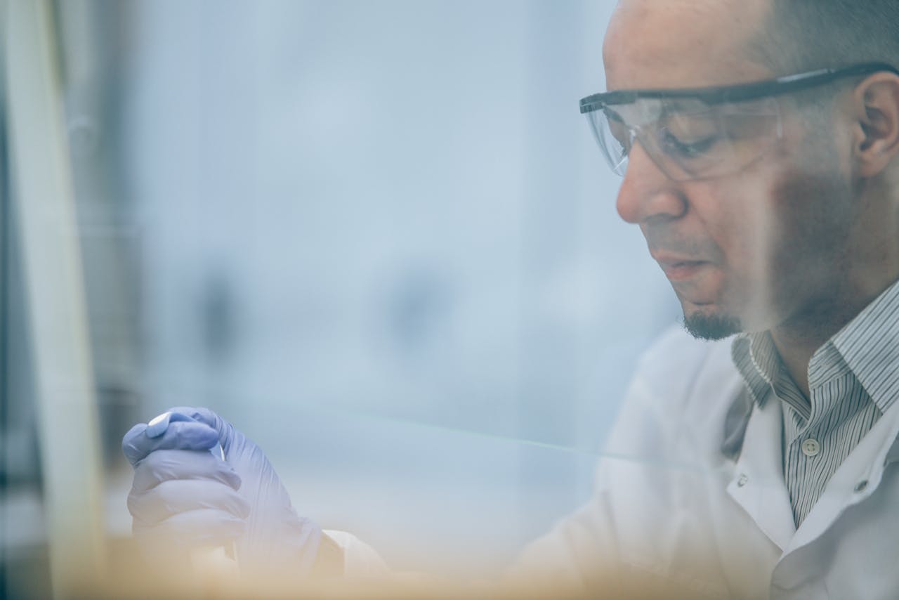 Research scientist wearing safety glasses and gloves in a laboratory setting.